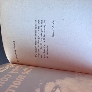 May include: A close-up of a book with a white cover and black text. The text reads "If we know, then we must fight for your life as though it were our own... For if they take you in the morning, they will be coming for us that night." The text is attributed to James Baldwin.