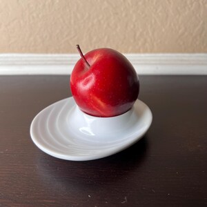 以下が含まれることがあります： 赤いリンゴが入った白いセラミック製のリンゴホルダー