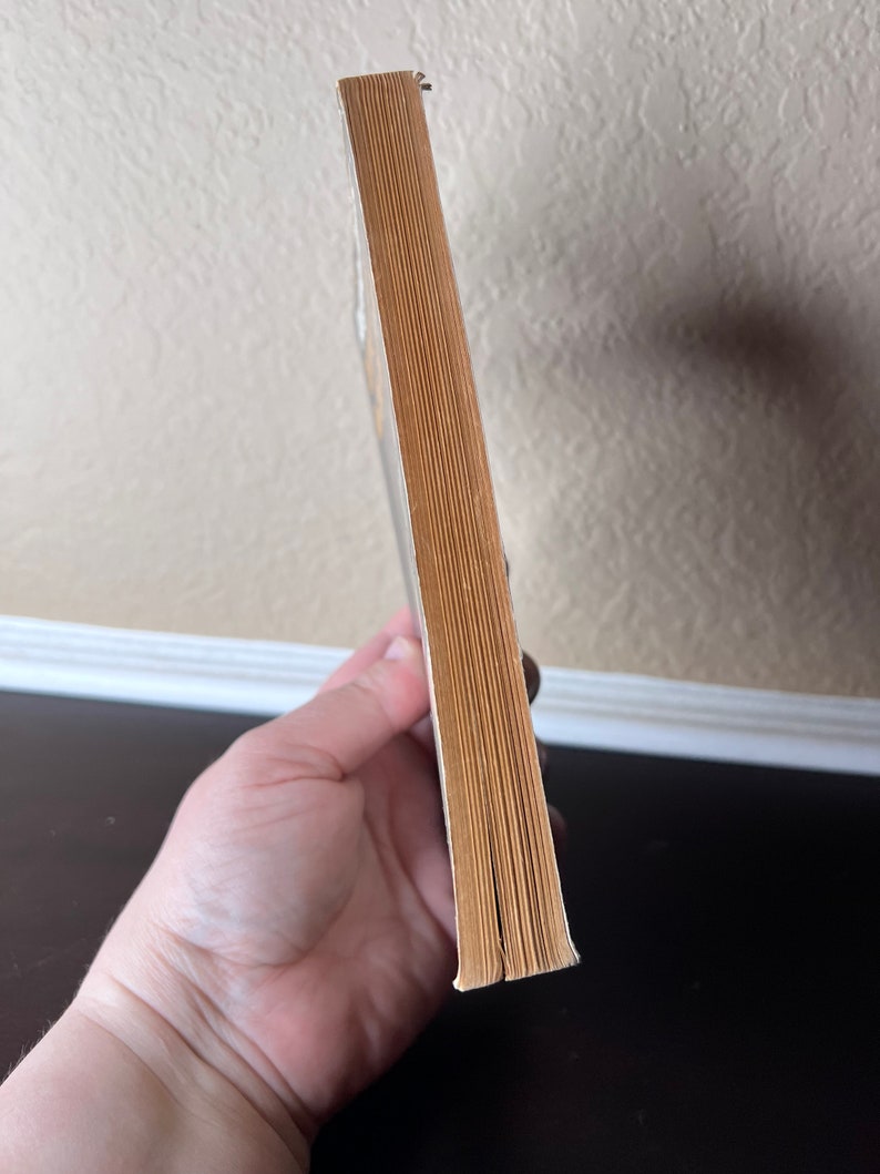 May include: The spine of a paperback book with a yellow cover. The book is closed and the spine is visible.