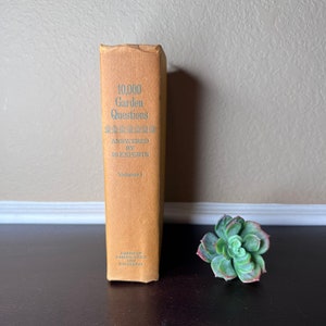Puede incluir: Un libro marrón titulado "10.000 preguntas de jardinería respondidas por 20 expertos" Volumen 1. El libro está publicado por American Garden Guild y Doubleday.