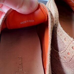 Puede incluir: Primer plano del interior de un zapato de ante marr&oacute;n con forro de cuero naranja. El zapato tiene una etiqueta que dice "Hecho en India".
