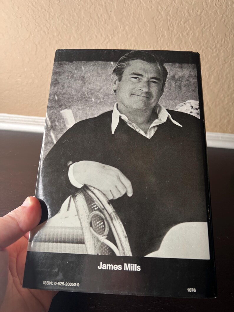 May include: Black and white book cover featuring a portrait of a man in a sweater and collared shirt. The name "James Mills" is printed in white at the bottom. The ISBN and a number are also visible.