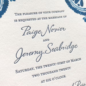 May include: Wedding invitation with blue and white floral design. The text reads "THE PLEASURE OF YOUR COMPANY IS REQUESTED AT THE MARRIAGE OF Paige Novier AND Jeremy Seabridge SATURDAY, THE TWENTY-FIRST OF MARCH TWO THOUSAND TWENTY AT SIX O'CLOCK"