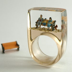 Family time – beige epoxy resin ring with a little family on a bench and a squirrel from Geschmeide unter Teck