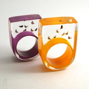 Butterflies – a winged resin ring with small colorful butterflies over an orange or purple ring