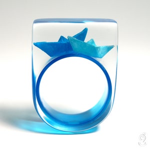Maritimer Boote-Ring "Schiff Ahoi" mit selbst gefalteten Mini-Booten aus hellbauem und blauem Papier auf blauem Ring in Epoxidharz