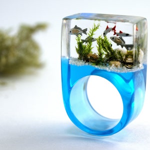 Etsy Design Awards Finalist 2020: Aquarium Fish ring with silver ornamental fish, sand, stones & moss on a blue ring made of resin gold & silver