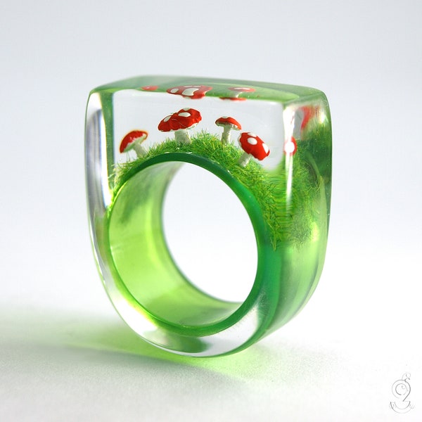 Goldiger Fliegenpilz-Ring – Fliegendes Glück – mit rot-weiß getupften Kunststoff Mini-Pilzen auf grünem Ring in Gießharz als Glücksbringer