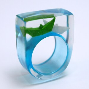 Ship ahoy maritime boat ring with hand-made folded mini boats made of light blue and blue paper on a blue ring made of resin white/green