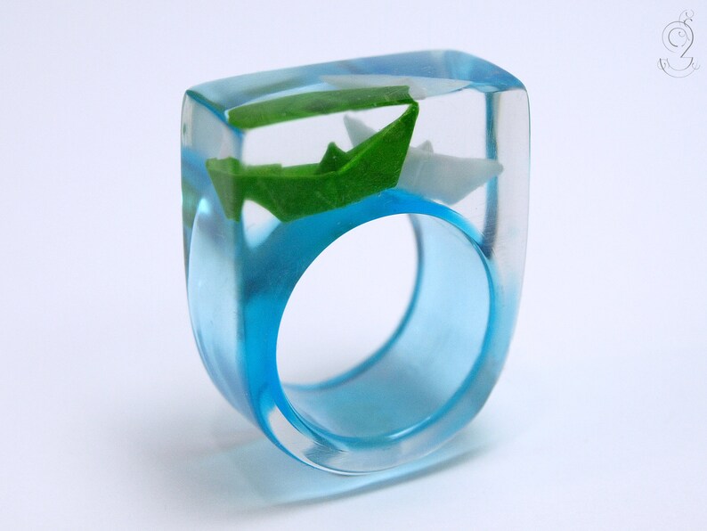 Ship ahoy maritime boat ring with hand-made folded mini boats made of light blue and blue paper on a blue ring made of resin white/green