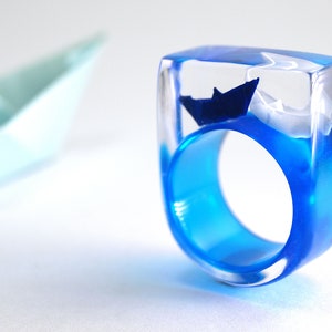 Ship ahoy maritime boat ring with hand-made folded mini boats made of light blue and blue paper on a blue ring made of resin white/blue