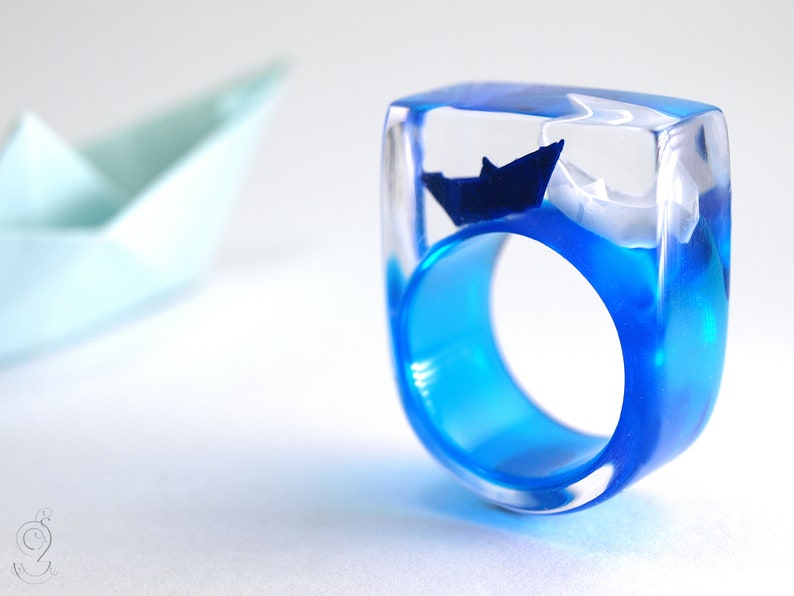 Ship ahoy maritime boat ring with hand-made folded mini boats made of light blue and blue paper on a blue ring made of resin white/blue