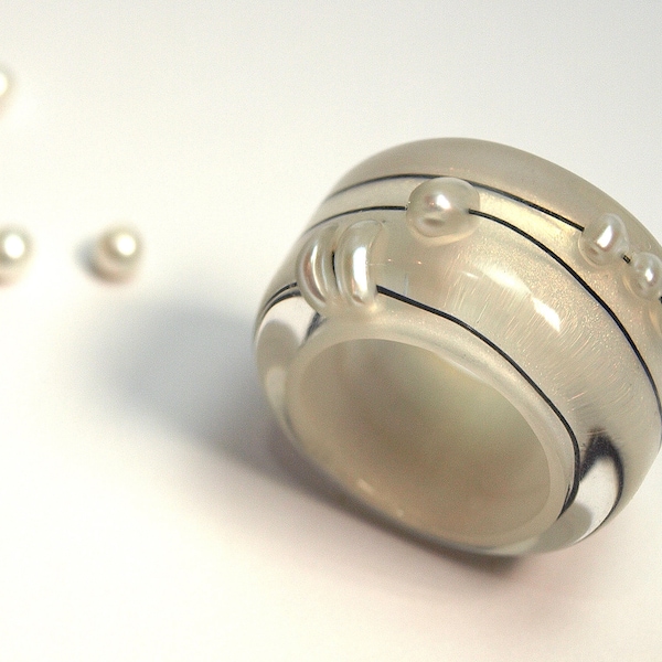 Abstracte parelring "Rundblick" gemaakt van giethars met echte witte parels en draad op een parelwitte ring