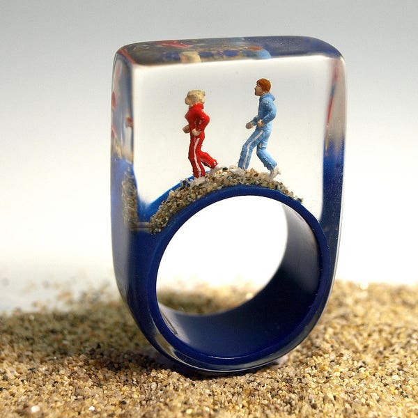 Early morning exercise – sportive jogger-figures ring with mini-figures and sand on a dark blue ring made of resin for the daily training