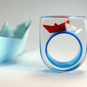 Ship ahoy maritime boat ring with hand-made folded mini boats made of light blue and blue paper on a blue ring made of resin white/red