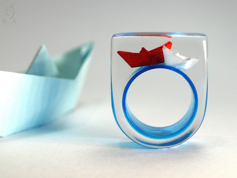 Ship ahoy maritime boat ring with hand-made folded mini boats made of light blue and blue paper on a blue ring made of resin white/red