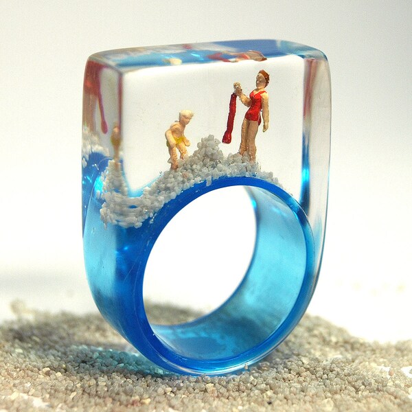 Sommerfrische – Sommerlicher Strand-Figuren-Ring mit Mini-Figuren und Sand auf hellblauem Ring in Gießharz für Urlaubsstimmung