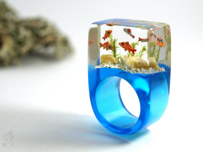 Etsy Design Awards Finalist 2020: Aquarium Fish ring with silver ornamental fish, sand, stones & moss on a blue ring made of resin orange & silver