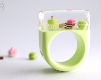 Sweet pastries – extraordinary treats ring with a petit fours and small treats on a pistachio ring with green lace made of resin