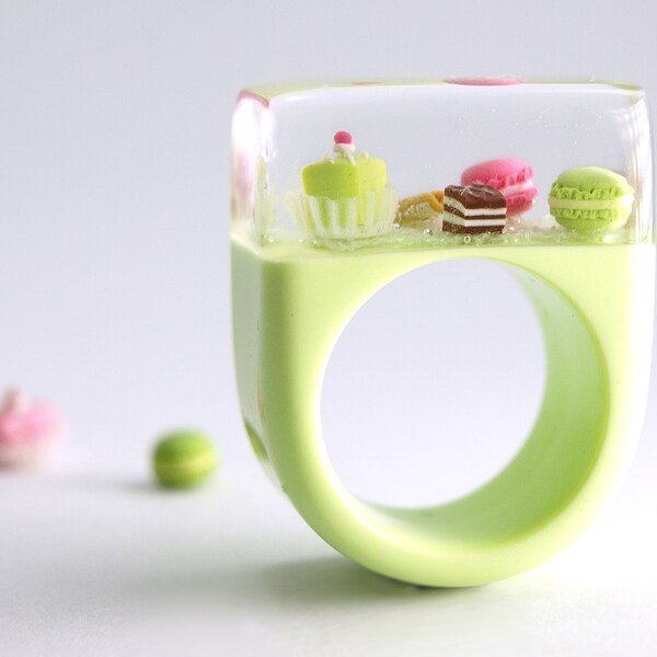 Sweet pastries – extraordinary treats ring with a petit fours and small treats on a pistachio ring with green lace made of resin