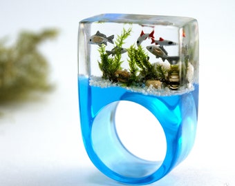 Finalista Etsy Design Awards 2020: Acquario – Anello con pesci ornamentali in argento, sabbia, pietre e muschio su un anello in resina blu