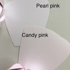 May include: Two pieces of paper in different shades of pink. The top piece is labeled "Pearl pink" and the bottom piece is labeled "Candy pink".