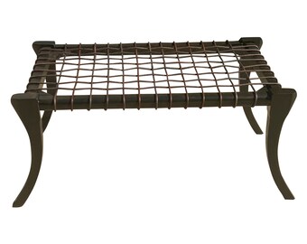 May include: A black wooden stool with a woven leather seat. The stool has a rectangular top and four legs that curve outward.
