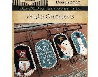 May include: Four winter-themed punch needle ornaments, each approximately 2 inches wide by 4 inches tall, with snowman and snowflake designs. The ornaments are displayed on a rustic metal rack. The text "Winter Ornaments" is visible.