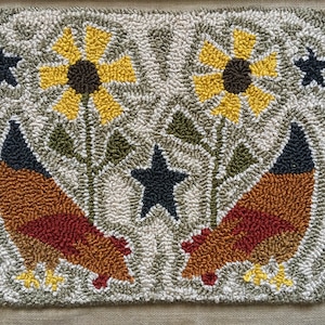 Pode incluir: Um tapete feito à mão com dois frangos castanhos e vermelhos com pés amarelos, dois girassóis amarelos com centros pretos e uma estrela preta sobre um fundo branco.