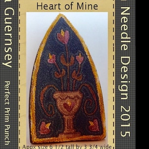 May include: A handcrafted, triangular rug with a dark blue background and a floral design. The rug features a vase with flowers and the text "Heart of Mine." Approximate size is 6.5 inches tall by 3.75 inches wide. The rug is a "Perfect Prim Punch" design.