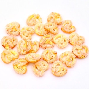 May include: A close-up of a pile of small, sugared pretzels. The pretzels are a light brown colour and are covered in white sugar crystals.
