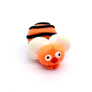 May include: A white ceramic mug with a black handle and the text "But First, Coffee" in a black, bold font. The mug is sitting on a wooden surface. The mug is approximately 4 inches tall.