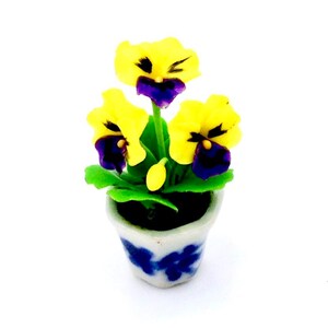 May include: A miniature potted plant with yellow and purple flowers in a blue and white ceramic pot. The plant is a miniature replica of a real plant and is perfect for dollhouses or other miniature settings.