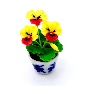 May include: A miniature potted plant with three yellow and red flowers in a blue and white ceramic pot.