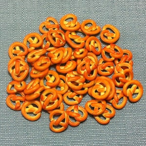 Op de afbeelding: Een grote stapel oranje pretzelsnacks op een blauw, getextureerd oppervlak.