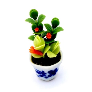 以下が含まれることがあります： 緑の葉、オレンジ色の花、青と白の模様の鉢植えのミニチュア植物。 ドールハウスやミニチュアコレクションに最適な、詳細で手作りの外観をしています。