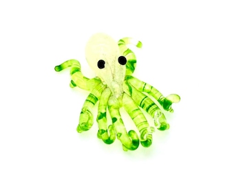 May include: A green and white glass octopus figurine with black eyes. The octopus has eight tentacles with a striped pattern.
