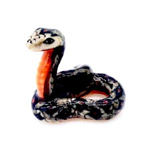 May include: A small ceramic snake figurine with black and white markings and an orange neck. The snake is curled up in a coil.