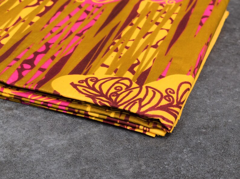 May include: A folded fabric with a yellow background and a pattern of pink and brown lines and floral designs.