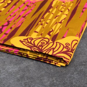 May include: Folded fabric with a vibrant pattern. The design features a combination of mustard yellow, hot pink, and burgundy. The pattern includes vertical lines and floral-like shapes, creating a bold and eye-catching textile.
