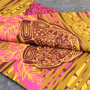 May include: A fabric with a repeating pattern of stylized flowers and geometric shapes in shades of pink, yellow, and brown.