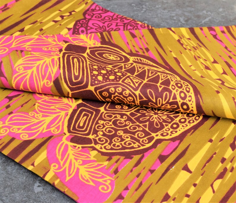 May include: A fabric with a repeating pattern of stylized flowers and geometric shapes in shades of pink, yellow, and brown.