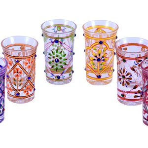 May include: A set of six clear glass tumblers, each featuring distinct hand-painted floral and geometric patterns in vibrant colors including purple, orange, green, yellow, and red, accented with small raised dots along the exterior surface.