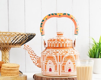 May include: A hand-painted orange kettle with white and green floral designs. The kettle has a traditional Indian design and is perfect for brewing tea.