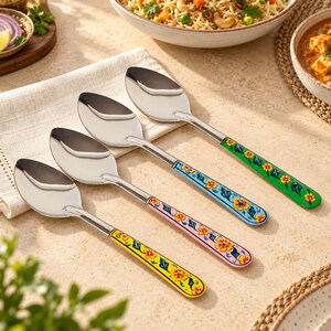 Könnte beinhalten: Ein Set aus vier Edelstahllöffeln mit dekorativen Griffen, die mit bunten Blumenmustern versehen sind. Die Griffe sind in Gelb, Rosa, Hellblau und Grün lackiert und jeweils mit gelben Blüten und grünen Blättern verziert.