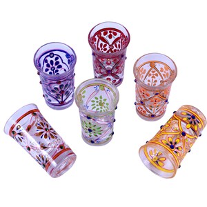 May include: A set of five clear glass tumblers, each decorated with distinct hand-painted floral and geometric patterns in vibrant colors including red, orange, purple, green, and yellow, featuring raised paint details along the exterior.