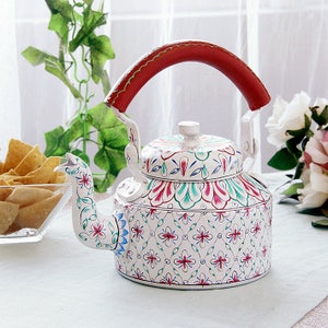 May include: White metal kettle with a red handle and floral designs in pink, blue, and green. The kettle has a spout shaped like a bird's head.