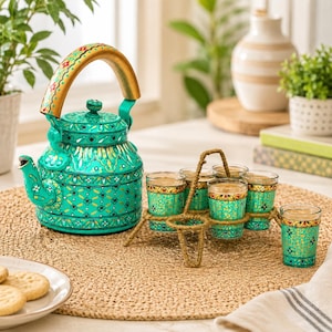 May include: A bright turquoise metal teapot with a gold-painted handle and intricate floral patterns, accompanied by a set of six matching small glass tumblers held in a woven wire carrier, all featuring consistent decorative gold and black details.