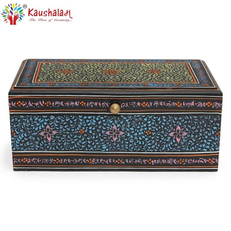 May include: A black wooden box with a floral design painted on the lid and sides. The box has a brass knob on the lid. The box is decorated with intricate floral patterns in shades of blue, pink, yellow, and orange.