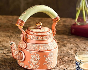 May include: A hand-painted orange kettle with a green handle and intricate floral designs. The kettle is made of metal and has a traditional Indian design.